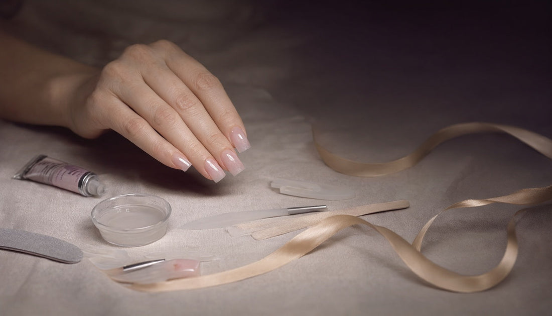 Poly gel nail extension tools and finished pink nails laid out on linen