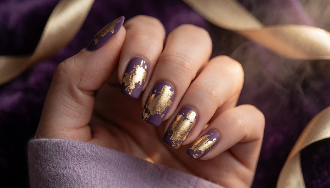 Hand with matte purple nails featuring a cracked gold foil texture